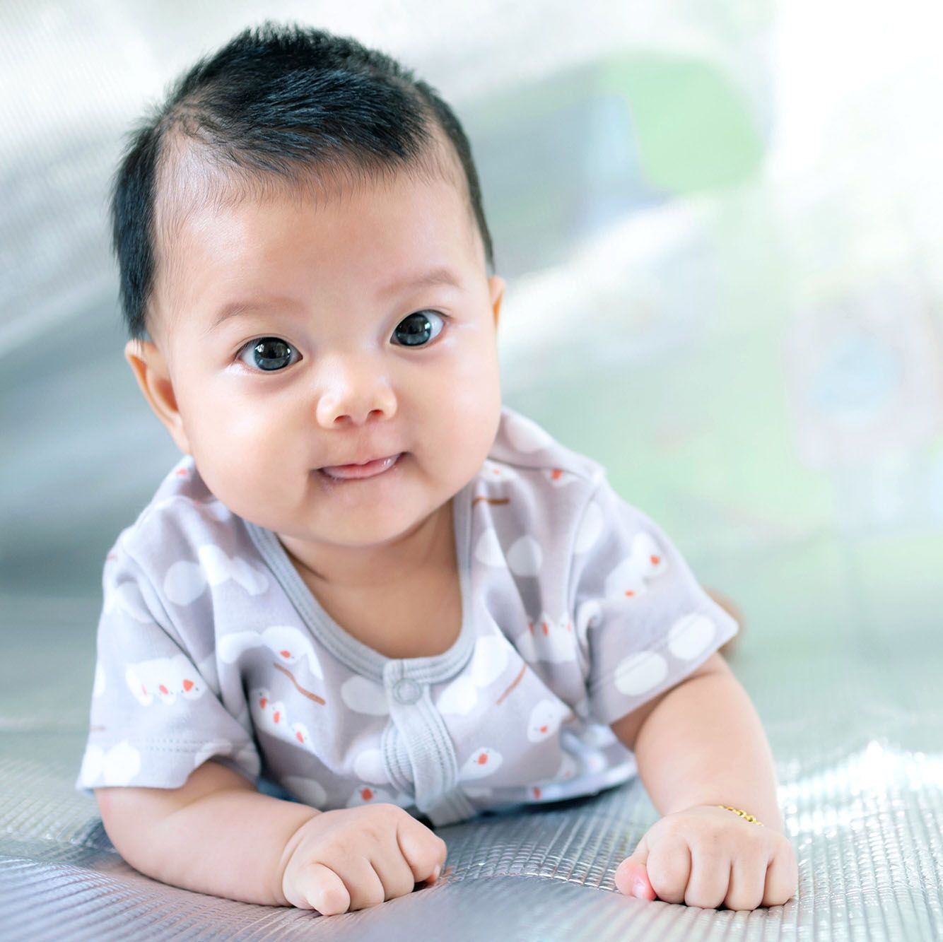 Topul despre nume de baieti arata ca un nou-nascut din Asia de Sud-Est se taraste pe podea nou-nascutul poarta camasa gri. Bebelusul este din Asia de Sud-Est. Copilul este dragut. Copilul face o fotografie in interior.